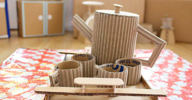 Hình ảnh một chú mèo đang vui vẻ chui vào một chiếc hộp carton được cắt cửa hình tròn, biến thành một hang trú ẩn đơn giản nhưng hấp dẫn.